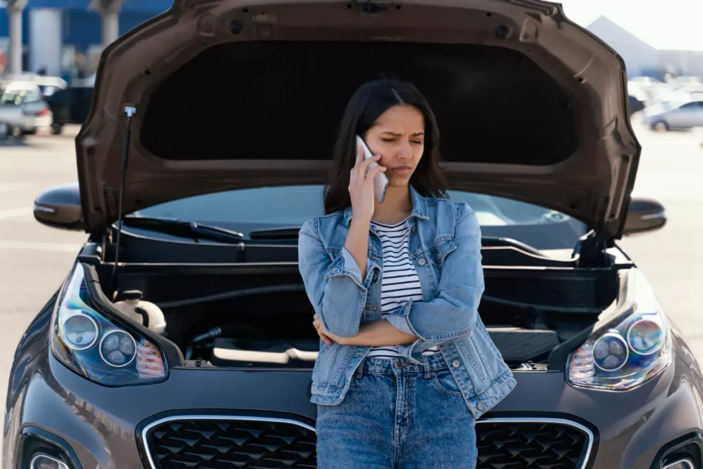 Mulher com o carro estragado ligando para ajuda no telefone